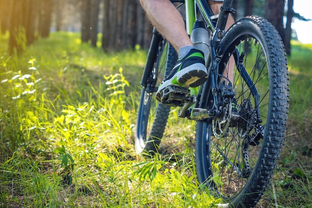 Ciclista em uma bicicleta de montanha verde nas madeiras que montam na grama. O conceito de estilo de vida ativo e extremo