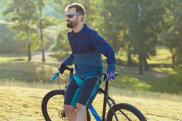 Foto ciclista em uma bicicleta hardtail de carbono moderna em um campo