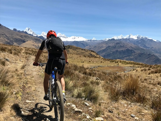 Ciclista de espalda alejandose cuesta abajo por un camino estrecho