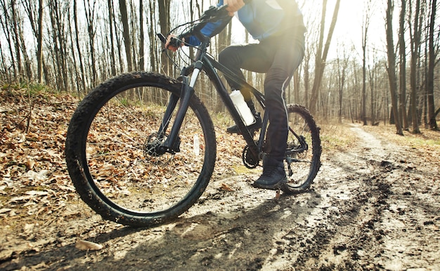 ciclista está andando de bicicleta de montanha na trilha de terra na floresta no início da primavera