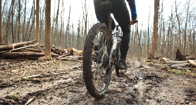 El ciclista está montando en bicicleta de montaña en un sendero de tierra en el bosque a principios de la primavera