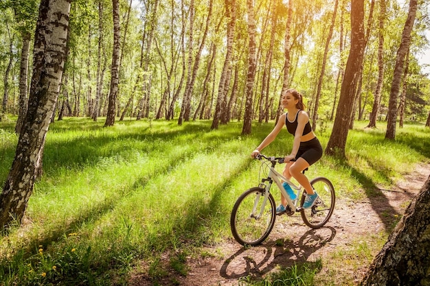 Ciclista feliz jovem andando de bicicleta na floresta de primavera