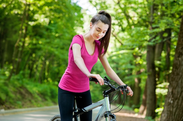 Ciclista femenina en una bicicleta en la carretera de asfalto en el bosque