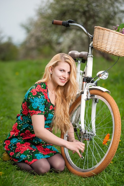 Ciclista feminina com bicicleta branca vintage no jardim primavera