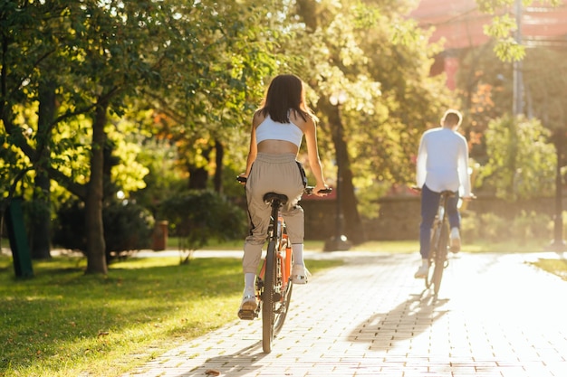 ciclista feminina em uma bicicleta laranja brilhante seguindo seu namorado ciclista em um parque da cidade moderna