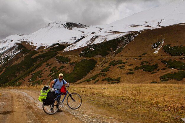 Ciclista en el fondo de montañas nevadas