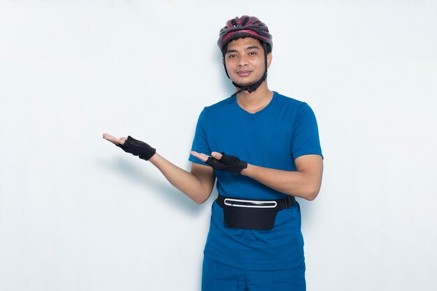 Ciclista joven apuesto apuntando con los dedos en diferentes direcciones sobre fondo blanco.