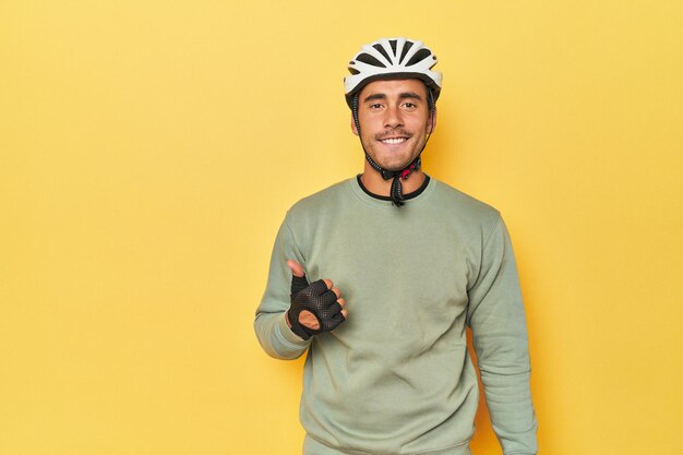 Foto ciclista latino vestido casual em amarelo sorrindo e levantando o polegar