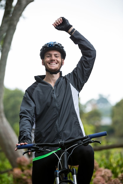 Ciclista masculina em pé com bicicleta de montanha no parque