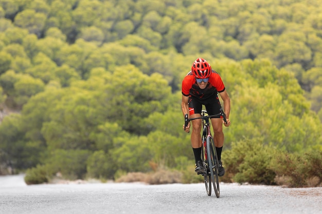 Foto ciclista masculino con casco entrenando en bicicleta al aire libre