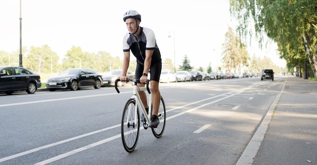 Un ciclista masculino con casco monta un entrenamiento en bicicleta en la ciudad
