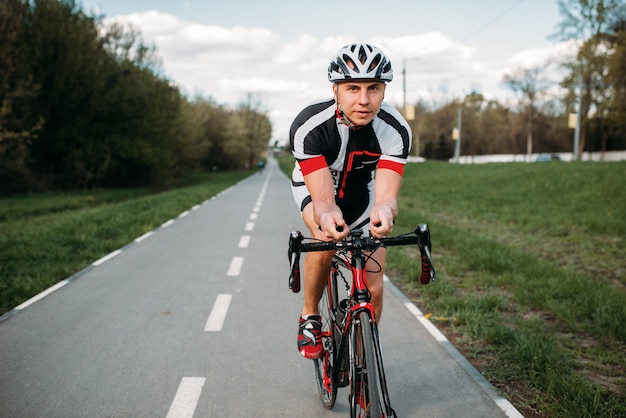Ciclista masculino en casco y ropa deportiva paseos en bicicleta