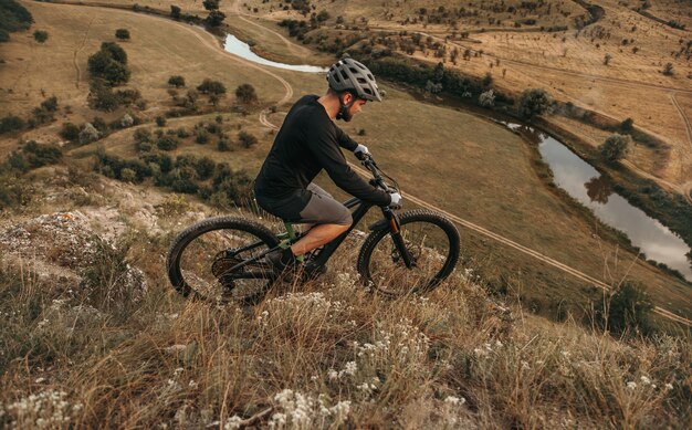 Ciclista masculino montando bicicleta de montaña en la ladera de la colina