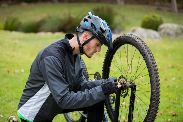 Ciclista masculino reparando su bicicleta de montaña