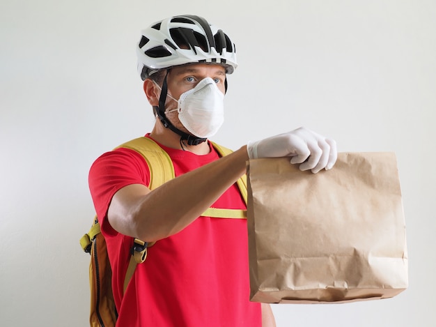 Foto el ciclista de mensajería está entregando la bolsa de papel. servicio de entrega durante coronavirus de cuarentena.