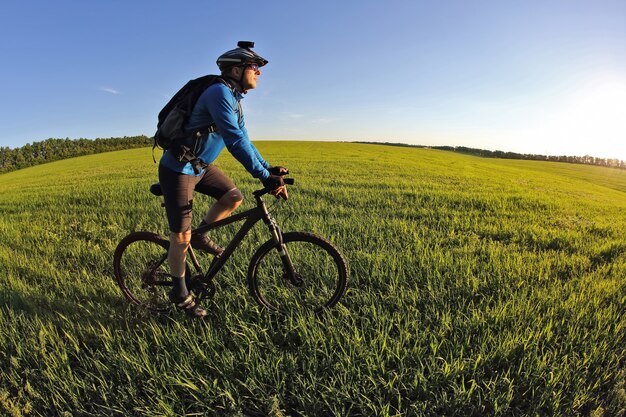 Ciclista monta una bicicleta en el campo verde hacia el sol