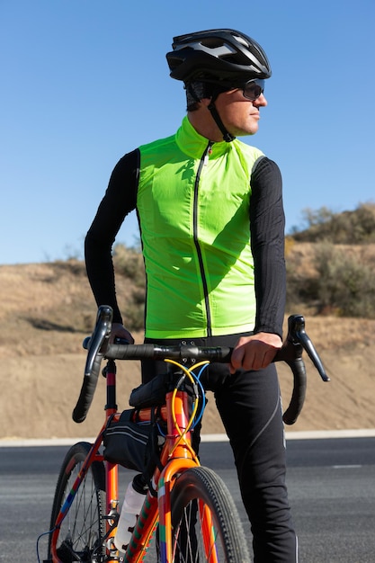 Ciclista montando bicicleta en la carretera contra el cielo despejado Un hombre con un traje se para con una bicicleta en un día soleado de otoño