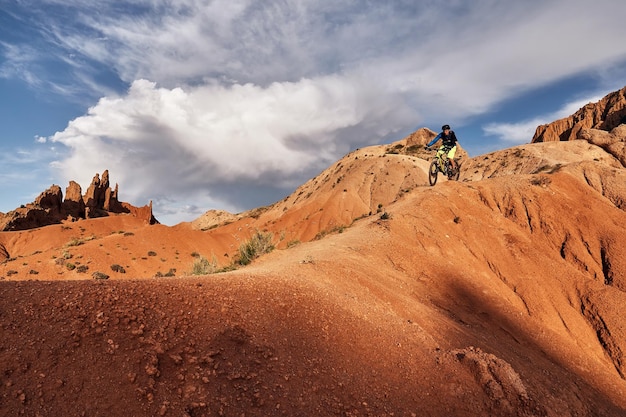 Ciclista montando una bicicleta de montaña al estilo cuesta abajo en un cañón Skazka, IssykKul, Kirguistán