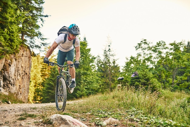 Ciclista montando la bicicleta en el sendero en el bosque Hombre en bicicleta en pista de enduro Motivación e inspiración para el fitness deportivo Concepto de deporte extremo Enfoque selectivo