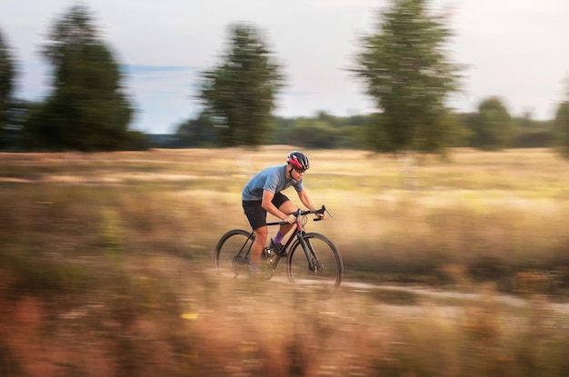 Ciclista en movimiento Joven deportivo monta bicicleta de grava a lo largo del sendero en el campo