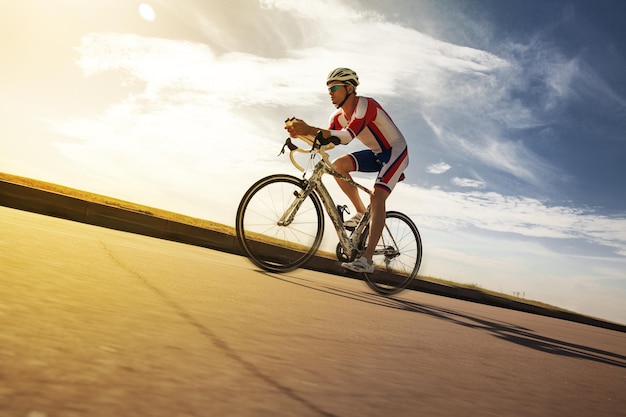 Ciclista en movimiento pedaleando en una bicicleta de carreras al aire libre al atardecer