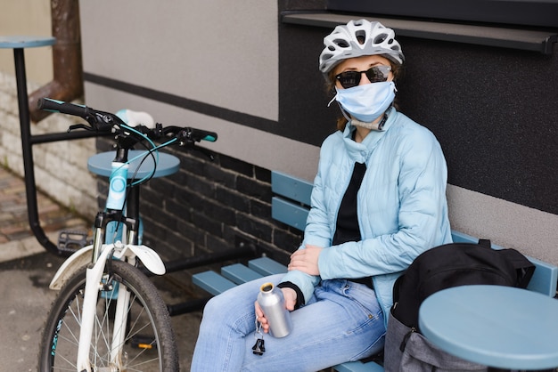 Ciclista de mujer en un casco y gafas de sol y máscara médica