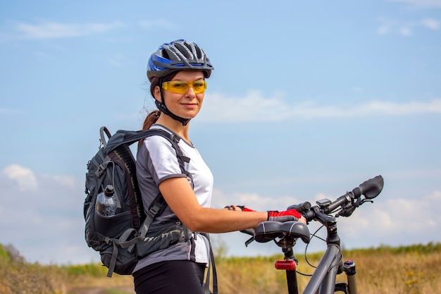 Ciclista de mujer hermosa con una bicicleta en la naturaleza