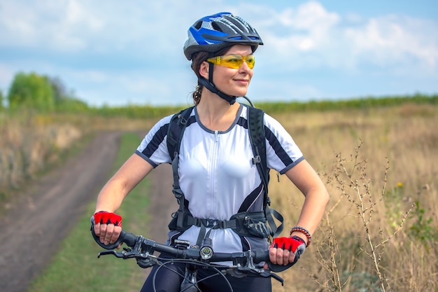 Ciclista de mujer hermosa y feliz con una bicicleta en la naturaleza. Estilo de vida saludable y deportes. Ocio y aficiones