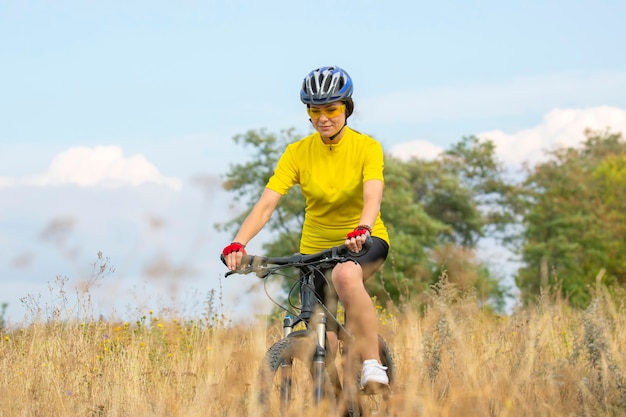 Ciclista de mujer hermosa paseos en el campo en bicicleta. Estilo de vida saludable y deporte. Ocio y aficiones