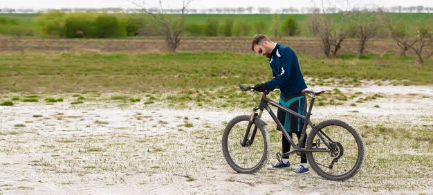 Ciclista de panorama en una bicicleta de montaña en una playa de sal sobre un fondo de juncos y un lago