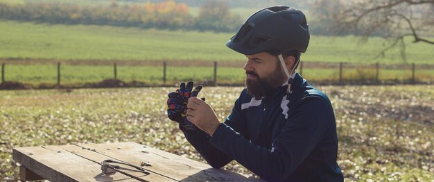 Ciclista con pantalones y chaqueta de lana en una moderna bicicleta de cola dura de carbono con horquilla de suspensión neumática paseos fuera de la carretera El tipo está descansando en un banco en el parque de otoño