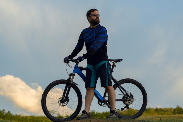 Ciclista con pantalones y chaqueta de lana en una moderna bicicleta rígida de carbono con horquilla de suspensión neumática El tipo en la cima de la colina anda en bicicleta