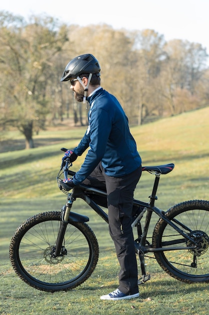 Ciclista con pantalones y chaqueta de lana en una moderna bicicleta rígida de carbono con horquilla de suspensión neumática El tipo en la cima de la colina anda en bicicleta