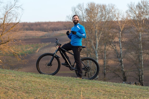 Ciclista con pantalones y chaqueta de lana en una moderna bicicleta rígida de carbono con horquilla de suspensión neumática El tipo en la cima de la colina anda en bicicleta