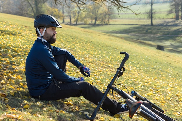 Ciclista con pantalones y chaqueta de lana en una moderna bicicleta rígida de carbono con horquilla de suspensión neumática el tipo en cima de la colina en bicicleta | Foto