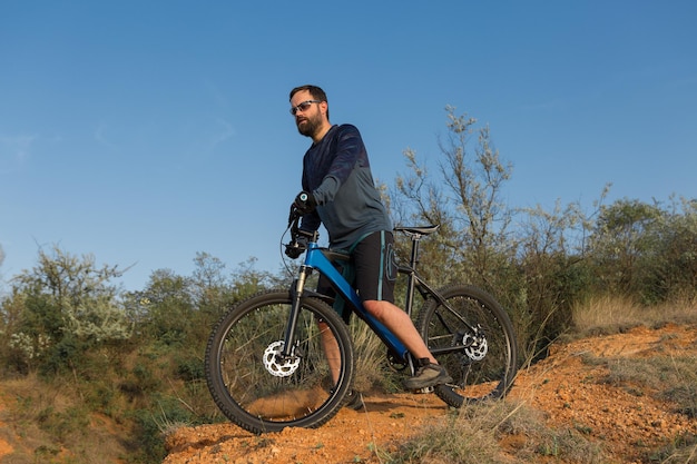 Ciclista en pantalones y chaqueta polar en una bicicleta moderna con una horquilla de suspensión neumática paseos offroad