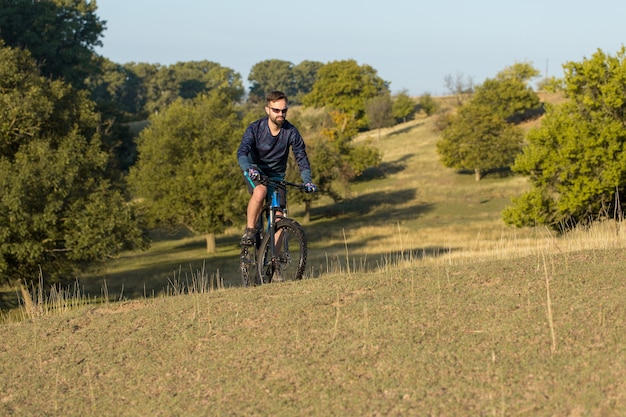 Ciclista en pantalones y chaqueta polar en una bicicleta rígida con una horquilla de suspensión neumática paseos offroad