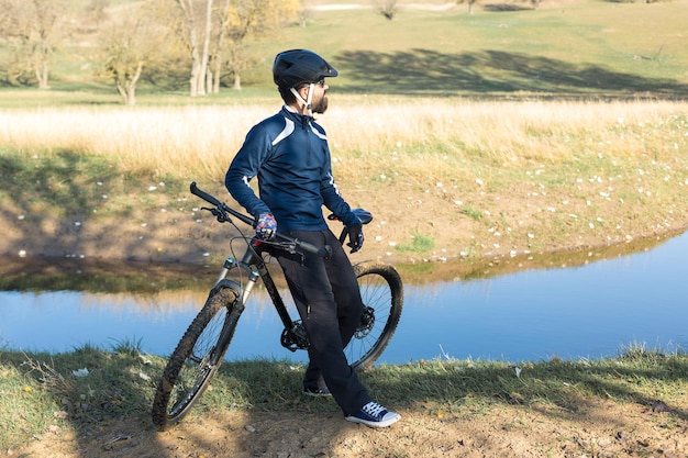 Ciclista con pantalones y chaqueta polar en una moderna bicicleta rígida de carbono con horquilla de suspensión neumática que recorre todo terreno