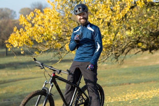 Ciclista en pantalones y chaqueta polar en una moderna bicicleta rígida de carbono con una horquilla de suspensión neumática