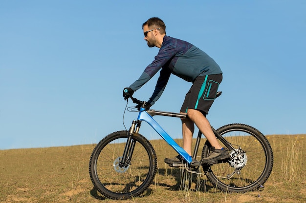 Ciclista en pantalones y chaqueta polar en una moderna bicicleta rígida con una horquilla de suspensión paseos offroad