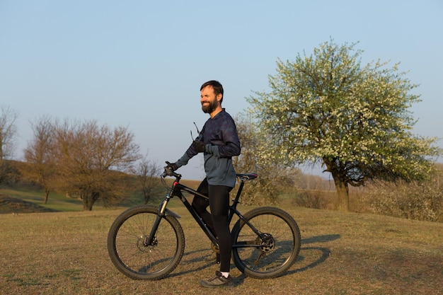 Ciclista en pantalones cortos y jersey en una bicicleta rígida de carbono con una horquilla de suspensión de pie sobre un acantilado