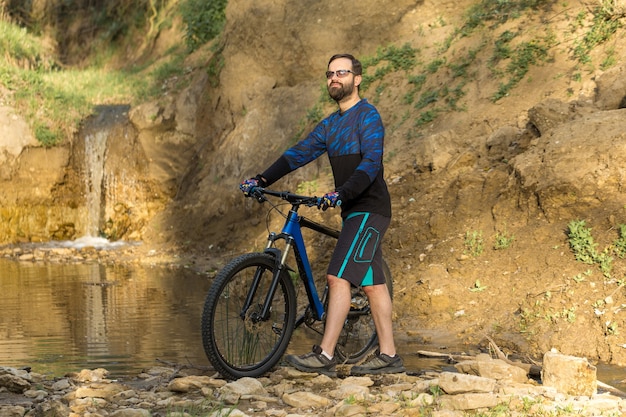 Ciclista en pantalones cortos y maillot en una moderna bicicleta rígida de carbono con una horquilla de suspensión neumática