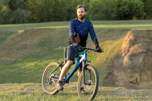 Ciclista en pantalones cortos y maillot en una moderna bicicleta rígida de carbono con una horquilla de suspensión neumática