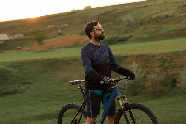 Ciclista en pantalones cortos y maillot en una moderna bicicleta rígida de carbono con una horquilla de suspensión neumática