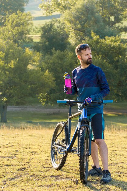 Ciclista en pantalones cortos y maillot en una moderna bicicleta rígida de carbono con horquilla de suspensión neumática