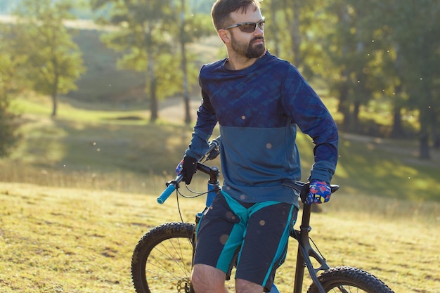 Ciclista en pantalones cortos y maillot en una moderna bicicleta rígida de carbono con horquilla de suspensión neumática