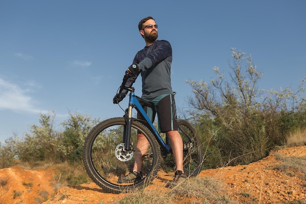 Ciclista en pantalones cortos y maillot en una moderna bicicleta rígida de carbono con horquilla de suspensión neumática