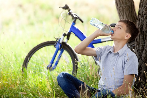 El ciclista en el parque bebiendo agua limpia.
