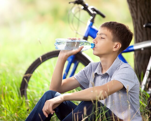 El ciclista en el parque bebiendo agua limpia.