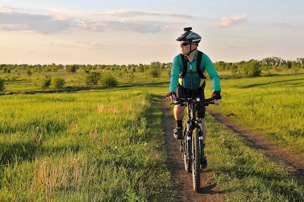 Ciclista paseos por la carretera en un campo en un día soleado